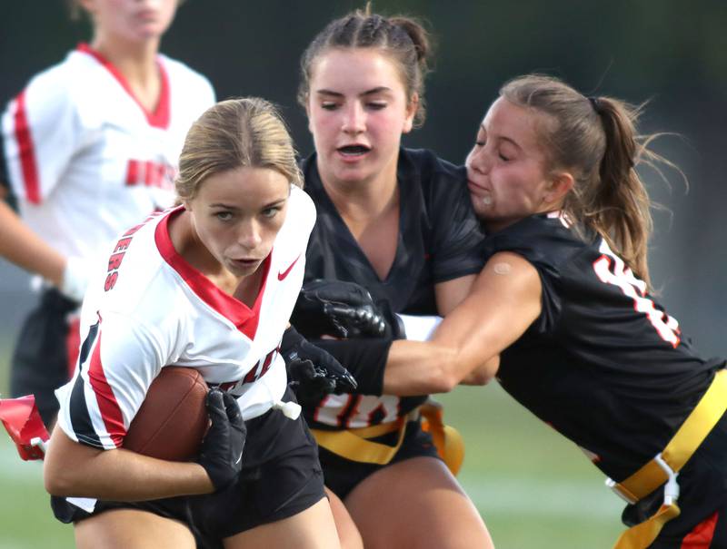 Huntley’s Madelyn McGhee, left, gets past a pair of Crystal Lake Central defenders in varsity flag football at Owen Metcalf Field on the campus of Crystal Lake Central High School in Crystal Lake on Tuesday, Sept. 16, 2025.