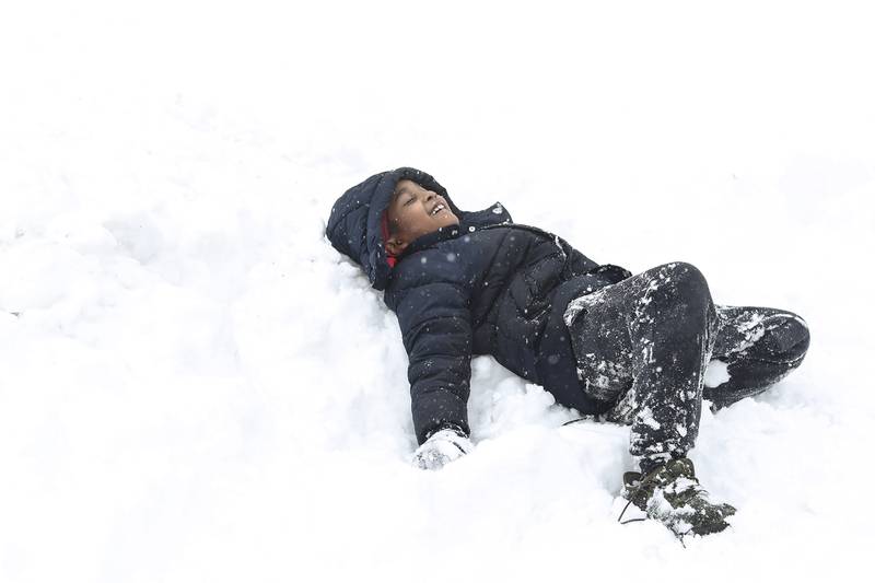 Derrick Stevenson III tries to make a snow angel on Sunday, Jan. 31, 2021, in front of his family's home in Joliet, Ill. Nearly a foot of snow covered Will County overnight, resulting in fun for some and challenges for others.