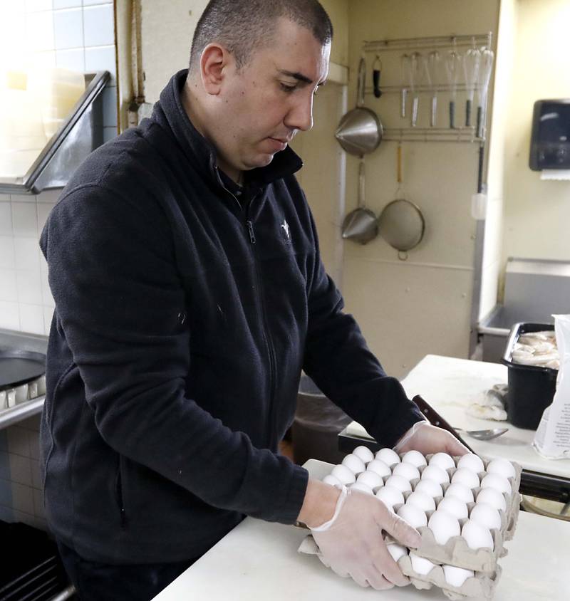 Angelo Angelos places  a container of eggs on the counter in the kitchen  on Friday, March 21, 2025, at Andy's Restaurant, in Crystal Lake.