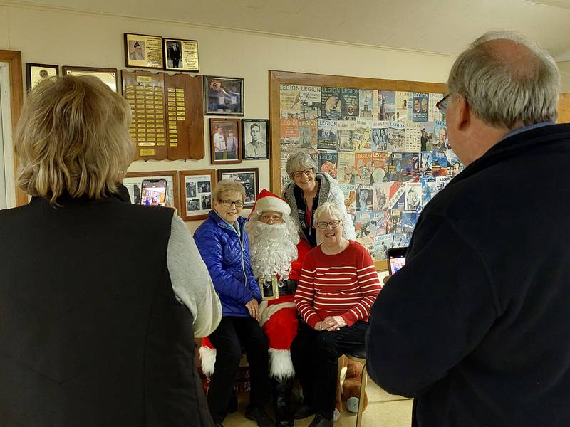 (From left) Rita Hofer, of Hennepin; Carol Monaco, of McNabb; and Donna Forney, of McNabb, sit on Santa's lap Saturday, Dec. 2, 2023, and get their picture taken during the Senior Christmas Carnival at the Granville American Legion.