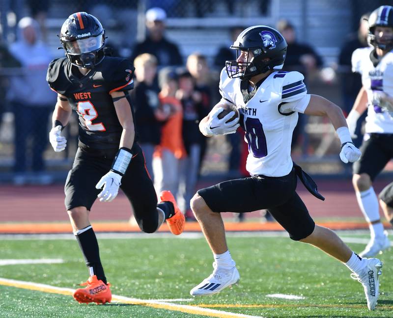 Downers Grove North's Oliver Thulin races past Lincoln-Way West's Braden Erwin (2) on a touchdown catch and run during an IHSA Class 7A quarterfinal game on Nov. 11, 2023 at Lincoln-Way West High School in New Lenox.