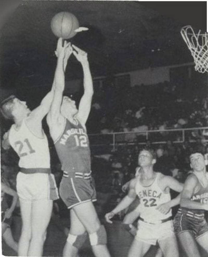 Frank Diss (21) leaps for a rebound over a Marseilles basketball player as Joe Billy (22) looks on in a 1959 Seneca Fighting Irish boys basketball game. The Irish will be playing this Friday's game against Henry-Senachwine in their old gym at the West Campus and welcoming back basketball alumni who played in that gym