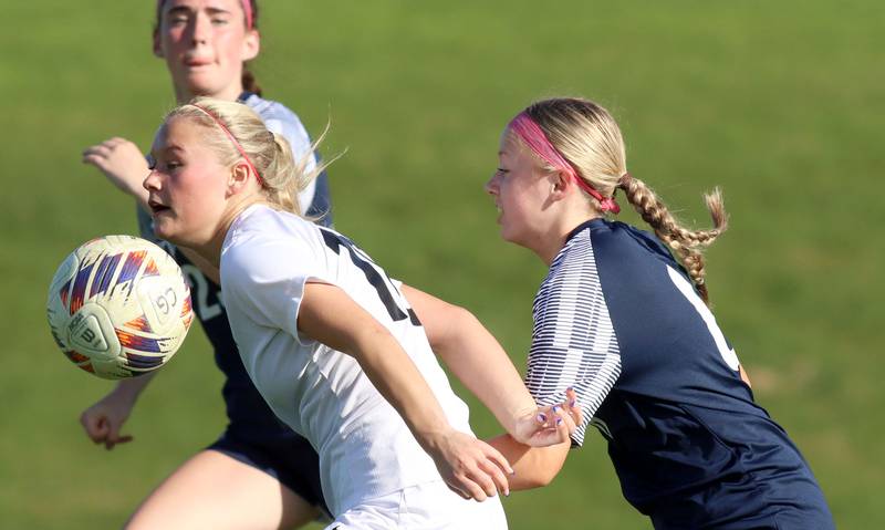 Prairie Ridge’s Maria Falkowska, center, uses her body to move the ball ahead of  Cary-Grove’s Julia Nichols, right,in varsity girls soccer at Cary-Grove High School in Cary on Tuesday, April 29, 2025.