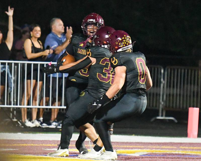 Montini Catholic's Payton Nelson, left, gets congratulated by teammates Santino Tenuta (32) and Laddie Asay (0) after a pick six during the game on Friday Sept. 19, 2025, while taking on Fenwick held at Montini Catholic High School.