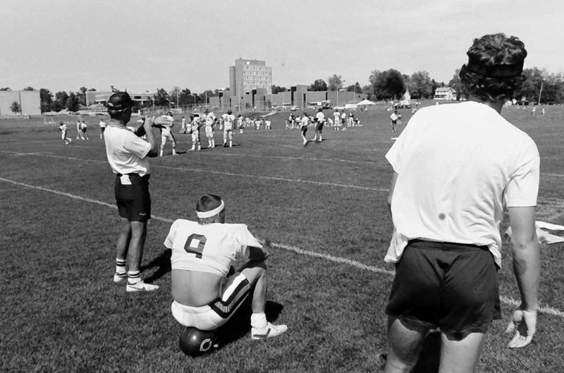 Chicago Bears quarterback Jim McMahon sits on a Chicago Bears helmet during training camp on Wednesday, June 12, 1985 in Platteville Wis.