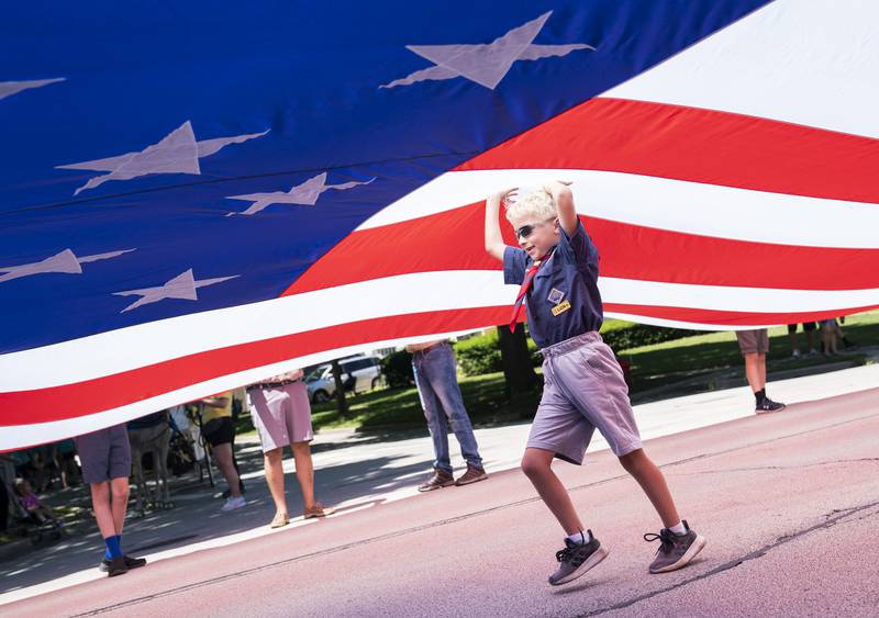 Ben Brown with Cub Scout Pack 111 of Geneva, holds up a giant American flag as the participates in the annual Swedish Days Parade in downtown Geneva on Sunday, June 26, 2022. The parade marked the last day of the festival which ran from June 22-26.