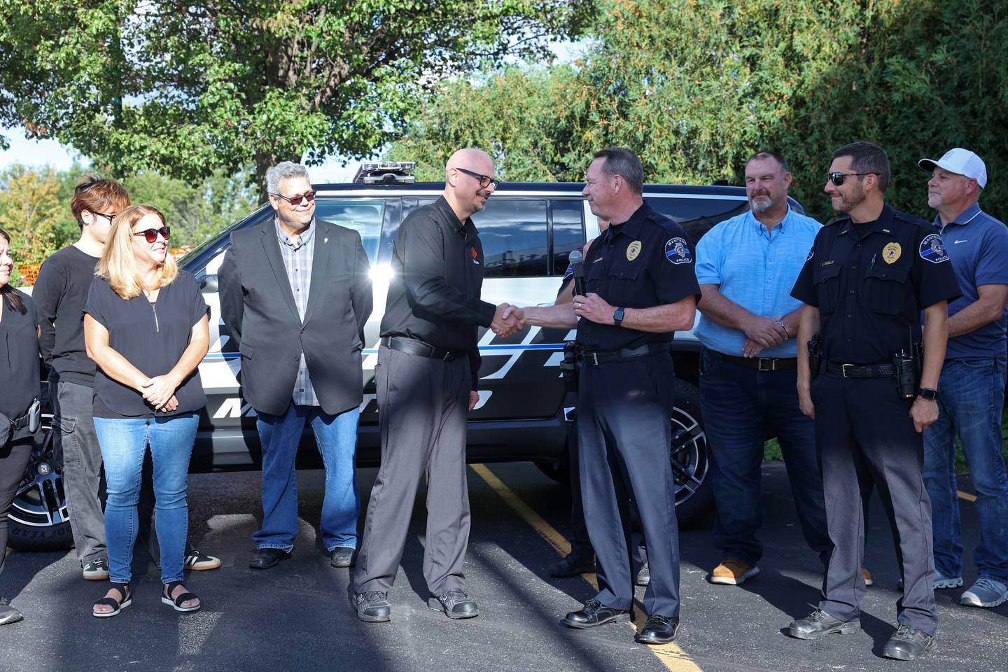 Gotion Vice President of Manufacturing Mark Kreusel, left center, handed the keys to the donated Rivian EV squad car to Manteno Chief of Police Alan Swinford, right center, on Thursday, Sept. 25, 2025, in a ceremony in downtown Manteno.