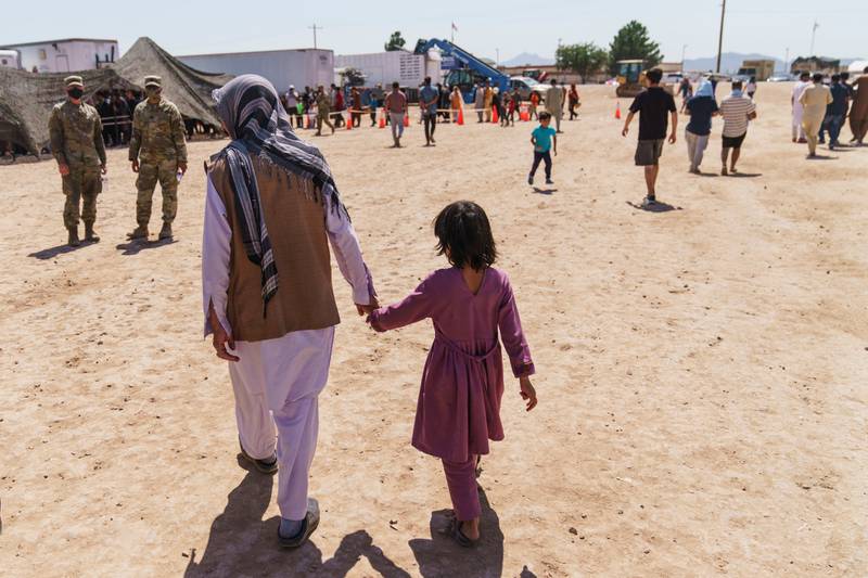 FILE - A man walks with a child through Fort Bliss' Doña Ana Village where Afghan refugees are being housed, in New Mexico, Friday, Sept. 10, 2021.   (AP Photo/David Goldman, File)