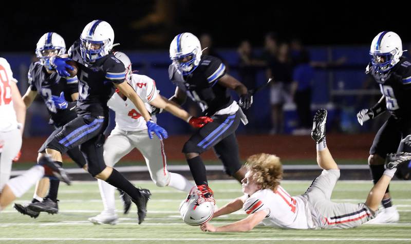St. Charles North's Anthony Taormina (5) turns upfield as Palatine's Trey Widlowski (11) loses his helmet in an attempted tackle Friday August 25, 2023 in St. Charles.