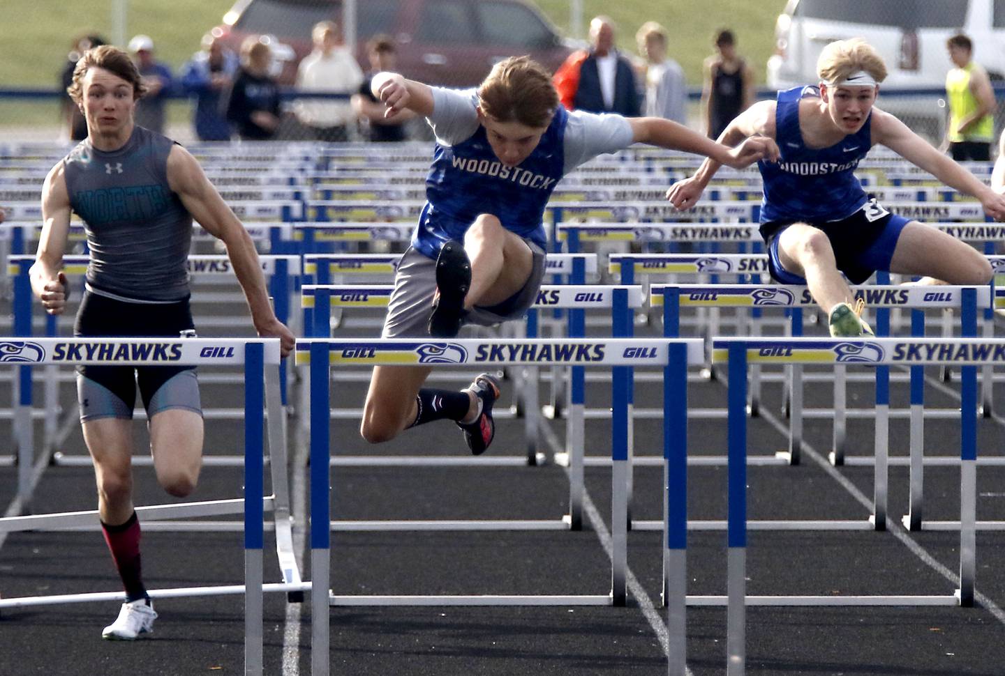 Woodstock’s Colton Medley (center) clears the last hurdle on the way to winning the 110 meter high hurdles in front of Woodstock North’s Braelan Creighton (left) and Woodstock’s Zach Kniola (right) during the Kishwaukee River Conference Boys Track and Field Meet on Tuesday, May 12, 2026, at Johnsburg High School.