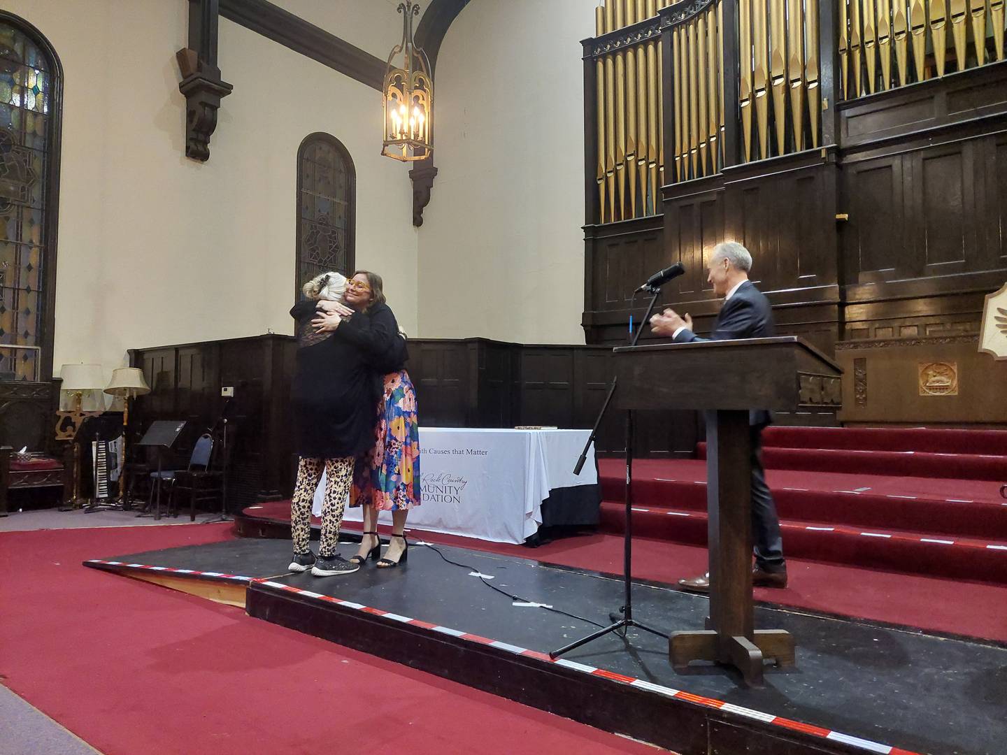 Susan Burton receives a hug from Amanda Weygand Zehr after Burton was announced as the lifetime achievement award winner Thursday, Feb. 1, 2024, at the OmniHonors Awards Celebration in Ottawa. Fran Brolley, CEO and president of Starved Rock Country Community Foundation, gives applause.