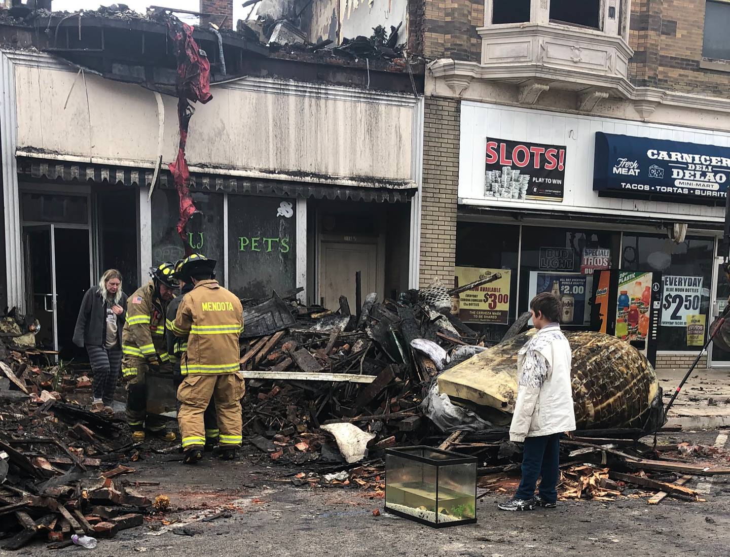 Firefighters carry fish tanks with surviving fish out of UJ Pet store after a fire caused the building to be a total loss on Friday, December 30, 2022.