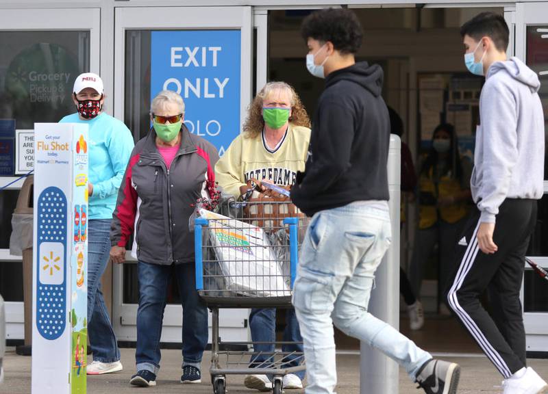 Shoppers in masks enter and exit the Walmart store on Sycamore Road in DeKalb Friday Nov. 20 on the first day of tightened restrictions on retailers and other businesses due to the recent surge in COVID-19 cases.
