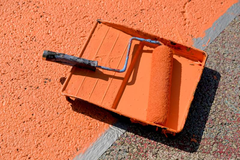 A paint tray of orange paint during the St. Charles Art Council’s “Paint the Riverside” to change out the street mural in the intersection of Walnut and Riverside Avenues on Saturday, May 10, 2025 in St. Charles.