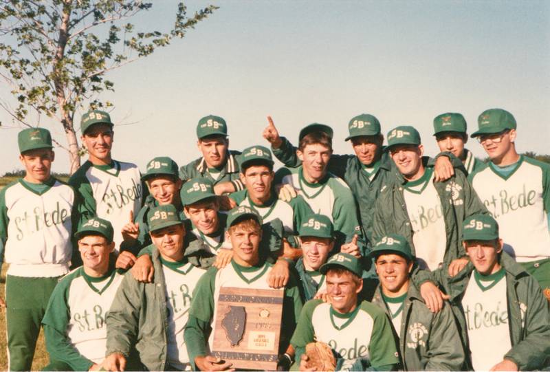 The 1988 St. Bede Bruins huddle up after defeating Mendota 5-4 for the regional championship at Putnam County. The Bruins won their final 10 games of the season, winning the Class A State championship. Team members are (front row, from left) Chad Kunkel, Brad Koster, Jim Perona, Steve Pomatto with trophy, Chris Clancy, Eric Bubelis, Mike DeAngelo and Chuck Loebach; and (back row) Jim Walsh, Ken Bima, Mark Schneider, Jim Barto, Brad Derix, Tom McGunnigal, Mike Schneider, Eric Krogulski, Sean Ginocchio and Mark Boucher.