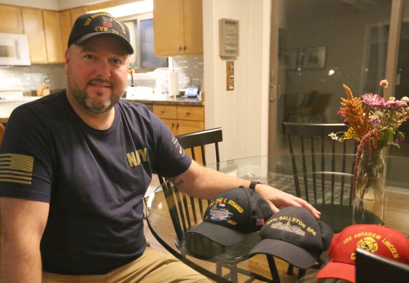 Navy Veteran Rich Jurden, who works at the La Salle nuclear power plant in Marseilles, poses with his display of veterans caps at his Ottawa home. Nautical drafting, shipbuilding and design were among the areas of the Navy he first looked to join, but it was suggested he take a test to work on nuclear aircraft. It would shape the rest of his career.