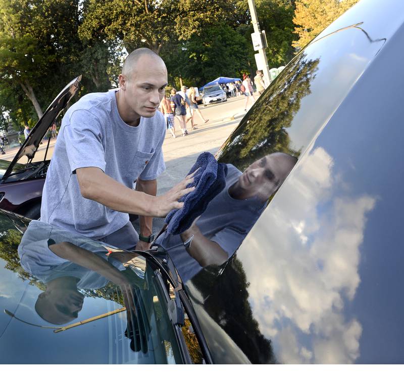 Jonathon Vickers helps a friend shine up this classic car along City Park during The Dream Machine Car Clubs Cruise night Saturday in Streator.