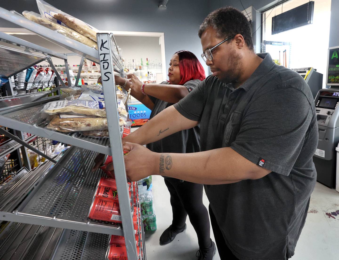 Demetrius Page and his wife Knenosha Fields-Page put items on the free food and drink shelf Thursday, Jan. 12, 2026, that they established at the Quick Stop Convenience Store in DeKalb. They created the shelf to benifit anyone who is in need that comes by.