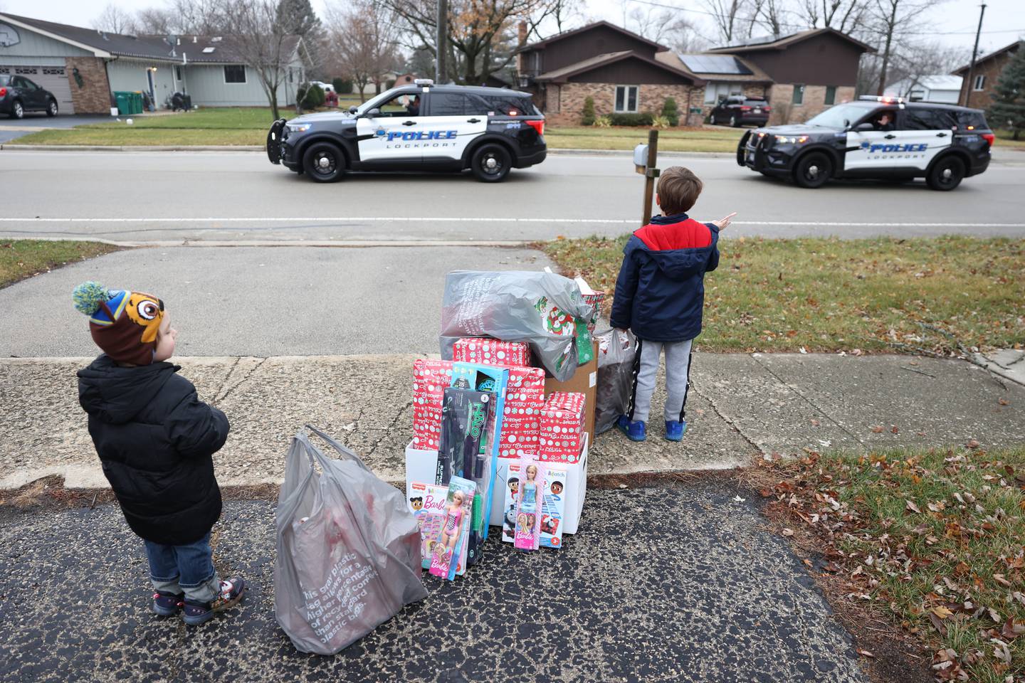 Ryder, 2, and Gage Jenicek, 5, wave to the Lockport Police as they leave after delivering gifts to the Jenicek family on Saturday, Dec. 10, 2022, in Lockport.