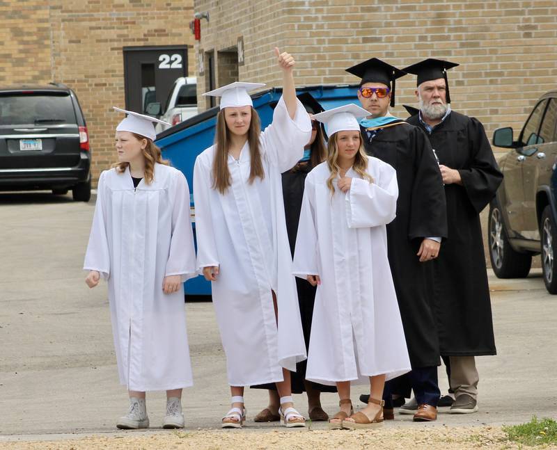 Junior Class officers kay Burger, Katie Drew and Jordyn Crawford  give a thumbs up signal to begin the processional on Sunday, May 28, 2023, during the Dixon High School graduation.