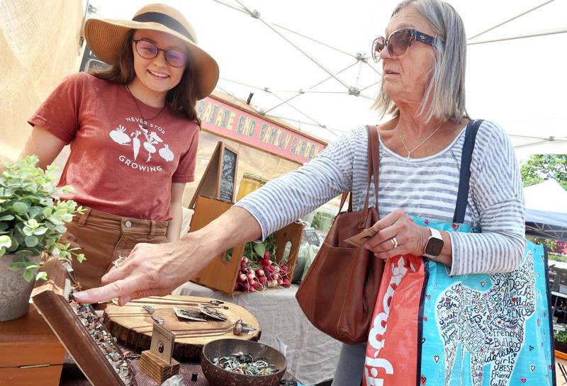 Jen Gontarek, (left) from Genoa, owner of Gratefully Dreaming, talks to Mary Hamell, of DeKalb, about birthstone rings she is selling at her booth Thursday, June 2, 2022, during the first DeKalb Farmers Market of the season at Van Buer Plaza in Downtown DeKalb.