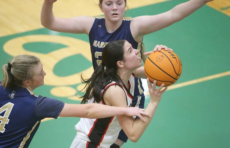 Amboy/Ohio's Tyrah Vaessen eyes the hoop while dribbling between Marquette defenders Hunter Hopkins and teammate Kelsey Cuchra during the Class 1A Regional championship on Thursday, Feb. 20, 2025 at St. Bede Academy.