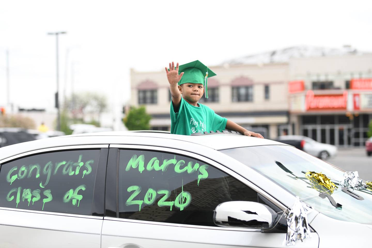 Preschooler Marcus Wiley waves to his teachers as he proceeds in the Play Palz 101 preschool graduation car parade, held in downtown Kankakee on May 14, 2020. The graduation theme song ‘Pomp and Circumstance’ played as teachers and staff formed a line to wave and cheer as students passed by, escorted by a Kankakee Fire truck and two squad cars, stopping at the end to retrieve their certificates from a social distance.