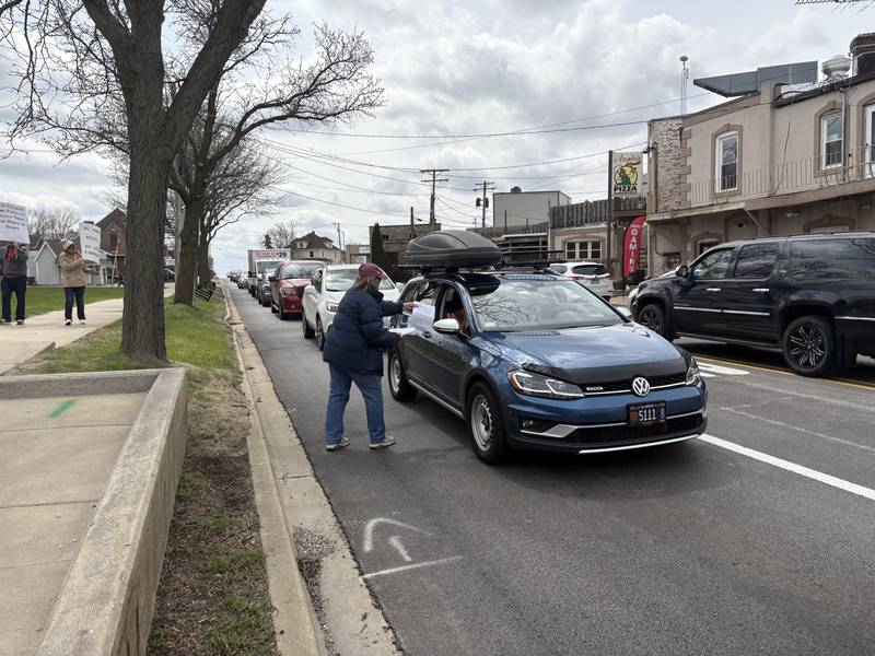 Diane Messman of Woodstock hands a flier to a driver in Harvard April 19, 2025.