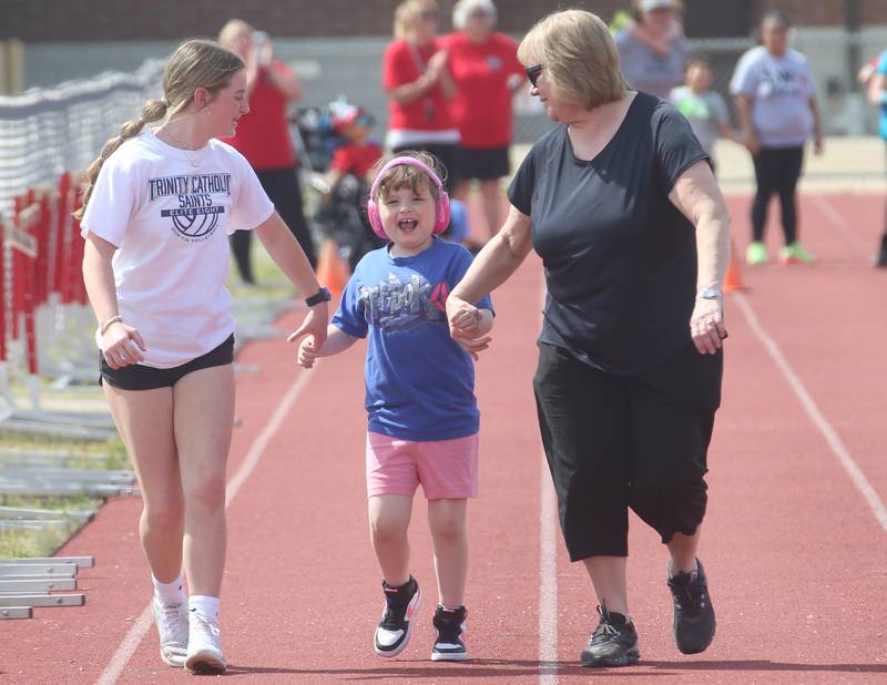 Lighted Way student Beverly (center) runs the track with the help of Trinity Catholic Academy eighth grader Payden Kelly and Chrisi Piano during the Lighted Way  and Trinity Catholic Academy PALS Spring Track Meet on Monday, May 13, 2024 at the L-P Athletic Complex in La Salle. Lighted way students participated in running, throwing, wheelchair slalom and much more.