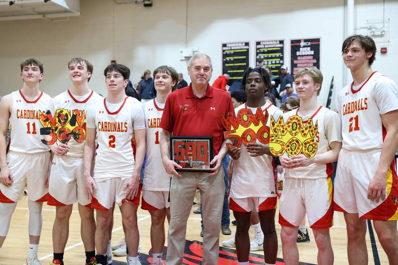 St. Anne head coach Rick Schoon, center, stands for a photo with his players following his 500th career win after the Cardinals secured a 64-43 victory over Momence in the River Valley Conference semifinals on Tuesday, Feb. 10, 2026.