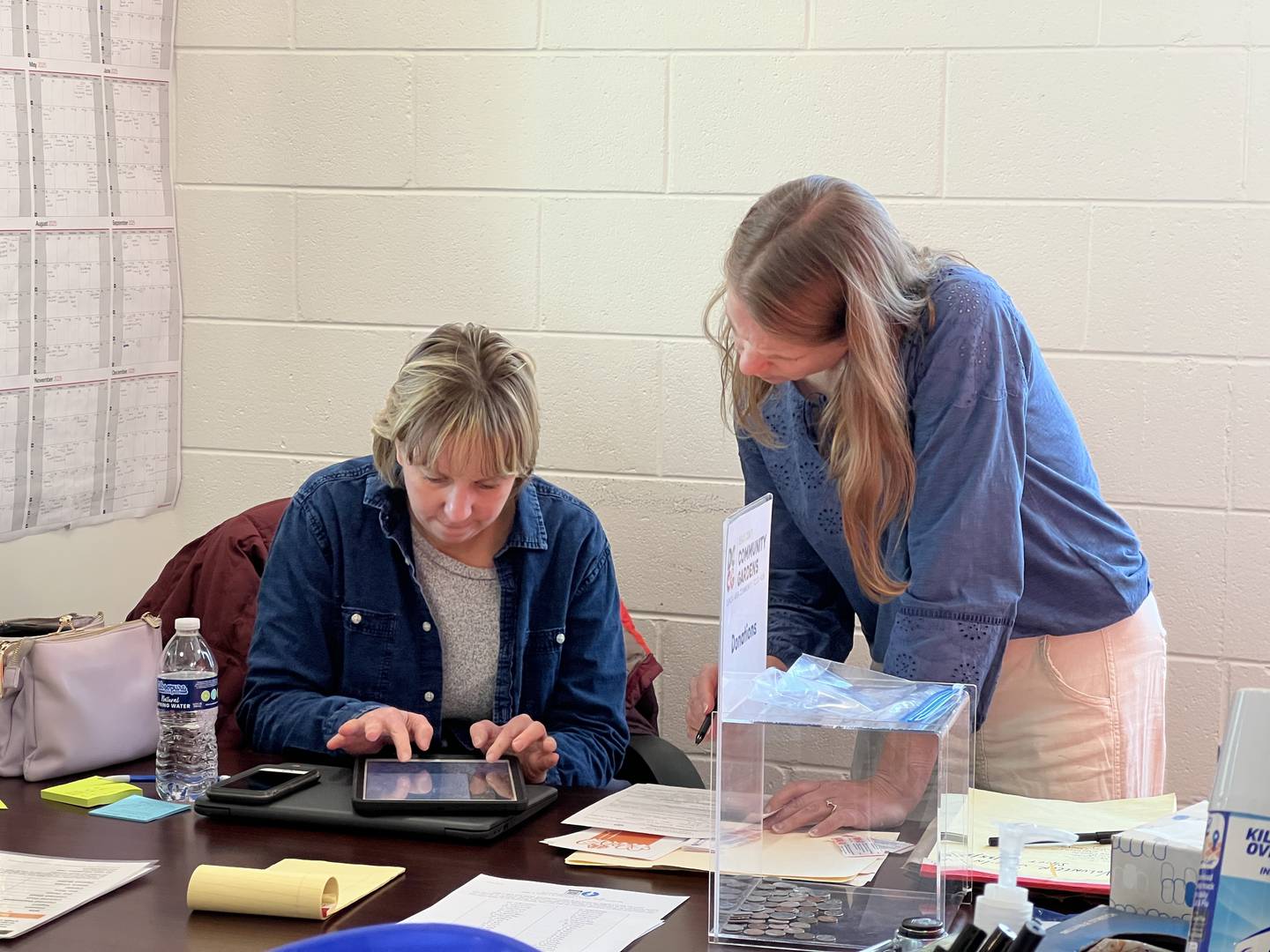 Genoa Area Community Food Hub Director Vicki Swierad tabulates the number of people who sought food during a food pantry event on March 25, 2025, while Rooted for Good Executive Director Heather Edwards watches.