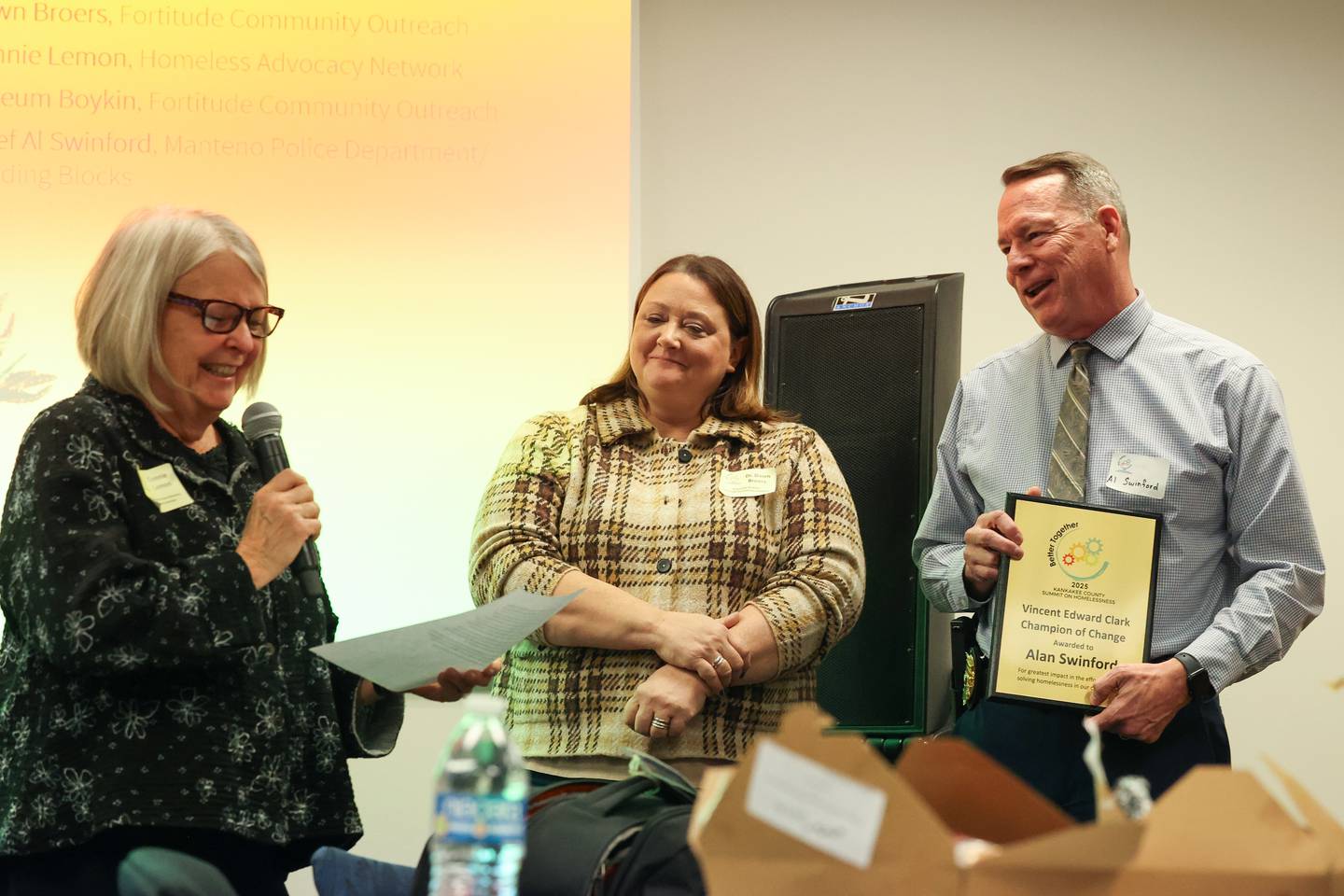 Manteno Police Chief Alan Swinford, right, receives the 2025 Vincent Edward Clark Champion of Change Award from Connie Lemon, left, and Dawn Broers during the third annual Kankakee County Summit on Homelessness on Thursday, Nov. 6, 2025, hosted by the Kankakee County Homeless Task Force at Kankakee Community College.
