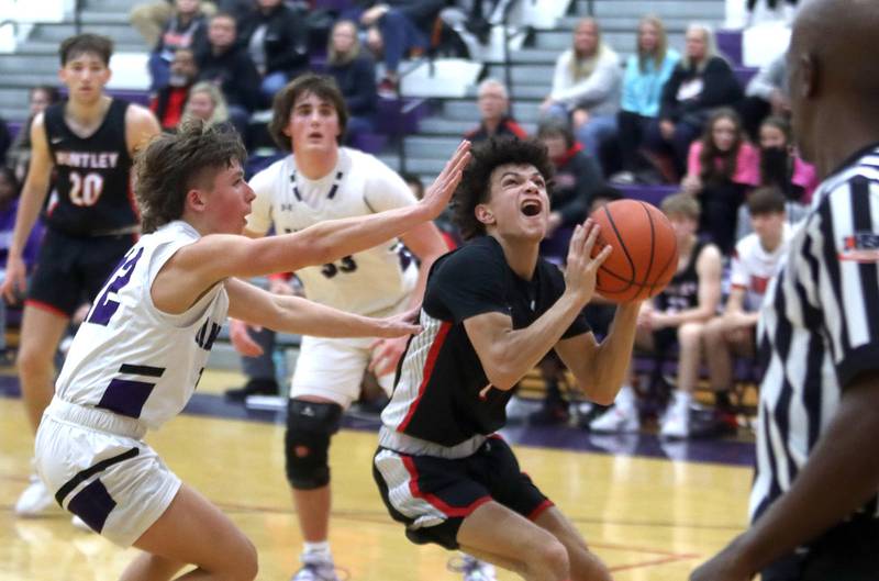 Huntley’s Lucas Crosby looks to the net as Hampshire’s Nick Louis, right, defends in boys basketball at Hampshire on Friday.