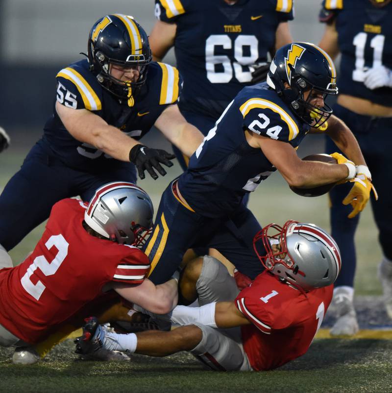 Glenbrook South's Tommy MacPherson carries the ball as he is tackled by Palatine's Josh Reiswig (2) and Rocco Paddack (1) during Thursday's game in Glenview.