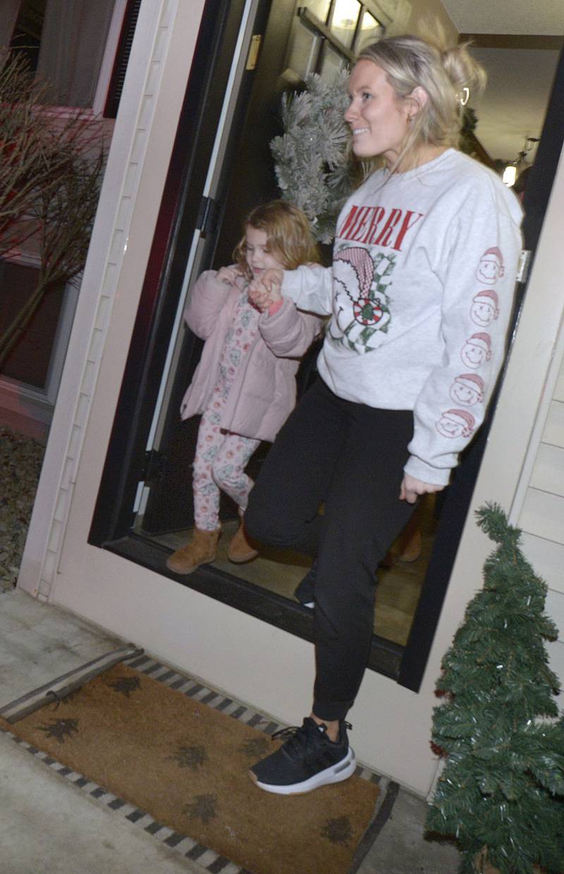 Quinn Thompson and her mother Sydney Thompson walk out their door to see the commotion outside as Santa arrives in a fire truck.