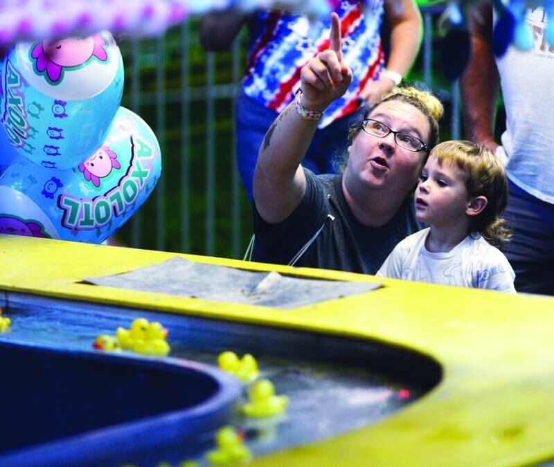 Alyssa Cadie of Chana helps Gunner, 3, pick out a toy at the duck pond carnival game during the Ogle County Fair on Thursday night, Aug. 1, 2024.