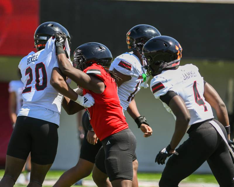 Northern Illinois University’s Telly Johnson Jr., center, blocks Chidu Bekee during practice on Saturday April 26, 2025, held at Huskie Stadium in DeKalb.