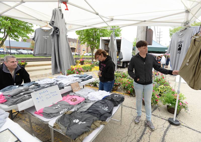 (left) Debra Anthony and Natalie Weedman of Downers Grove look over the t-shirts made by Glen Kato of Oak Lawn during the Downers Grove Farmers Market Saturday May 13, 2023.