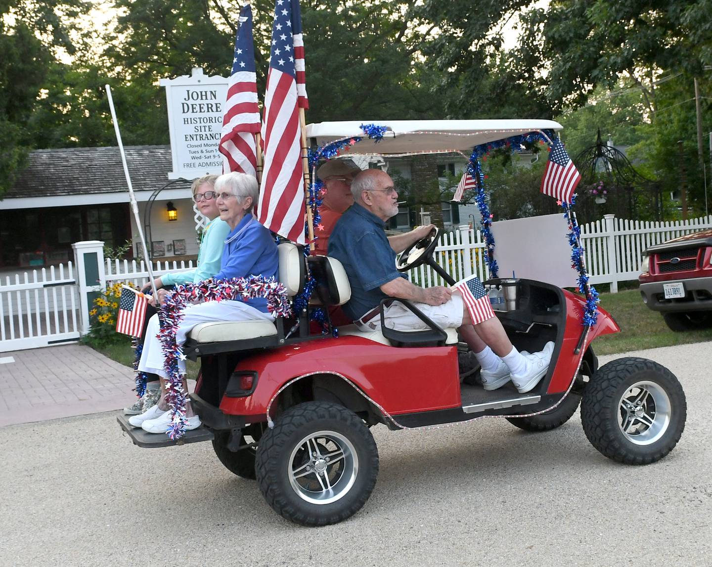 Roger and Joan Kelly, this year's Grand Marshals for the Grand Detour Golf Cart Parade, ride past the John Deere Historic Site at the start of the July 3 parade. The couple used to live in Grand Detour and were the owners of the Ace Hardware store in Dixon. Rich Kelly, a current owner of the store, was their driver.