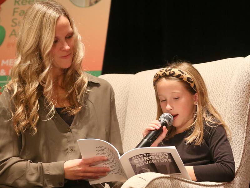 Author Reese Carney 8, of Utica (right), reads a passage with her mother Emily out of her  book titled "Reeses Fantastic Surgery Adventure" on Monday, Nov. 6, 2023 in Matthiessen Auditorium at La Salle-Peru Township High School.