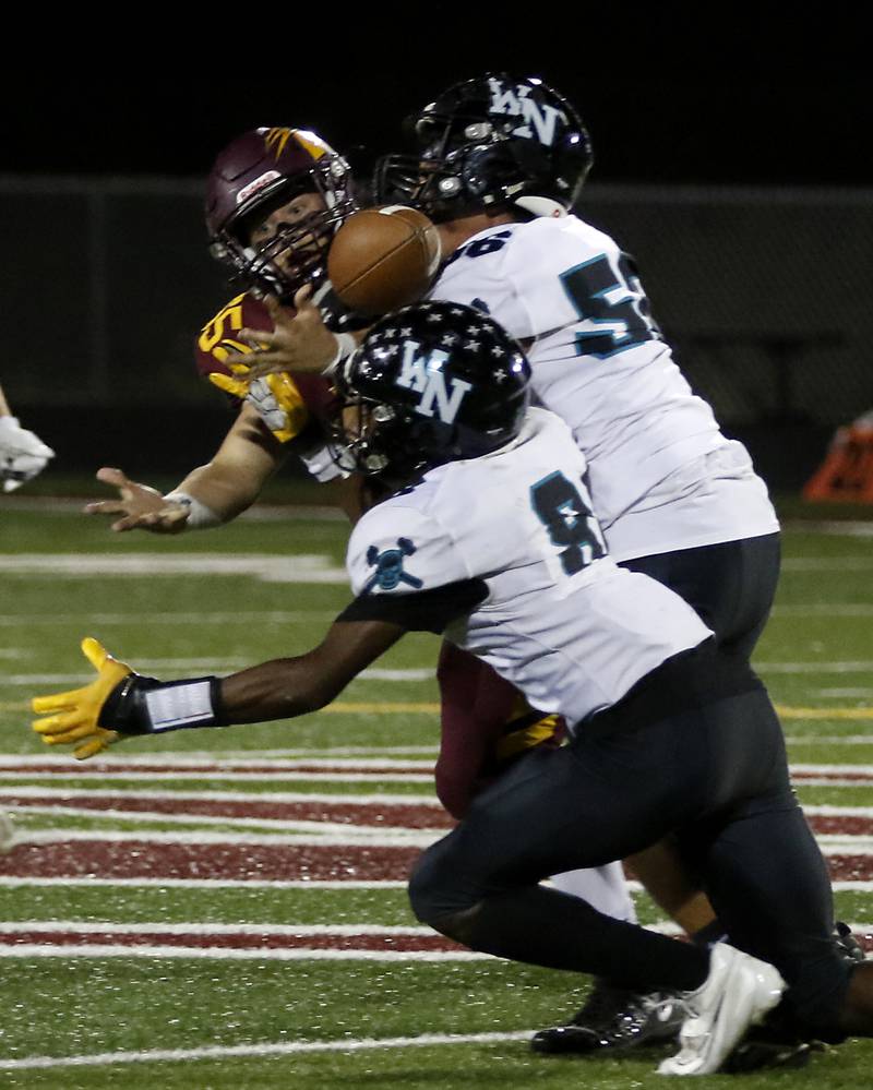 Richmond-Burton's Trevor Szumanski breaks up a pass intended for Woodstock North's Maxwell Dennison as Woodstock North's Julian Segura also tries to come up with the football during a Kishwaukee River Conference football game on Friday, Oct. 11, 2024, at Richmond-Burton High School.