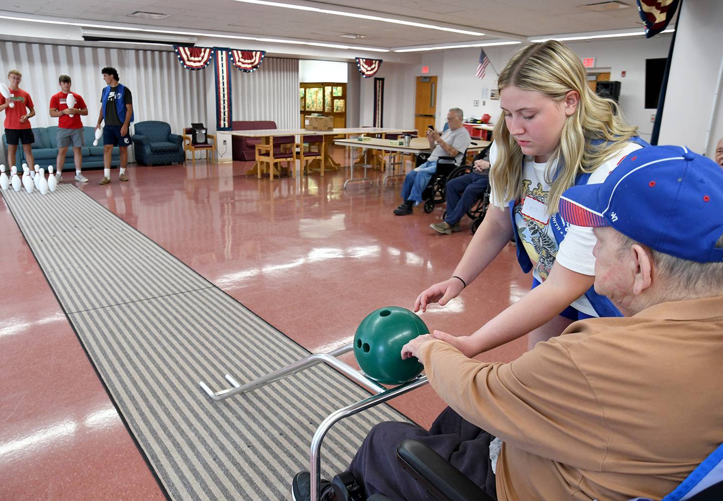 LaSalle-Peru Township High School girls basketball player Lana Eltrevoog assists one of the Illinois Veterans Home at LaSalle residents while bowling on Thursday. Members of the L-P boys and girls basketball programs spent time Wednesday and Thursday volunteering with activities on Thursday, July 27, 2023 at the Illinois Veterans Home in La Salle.