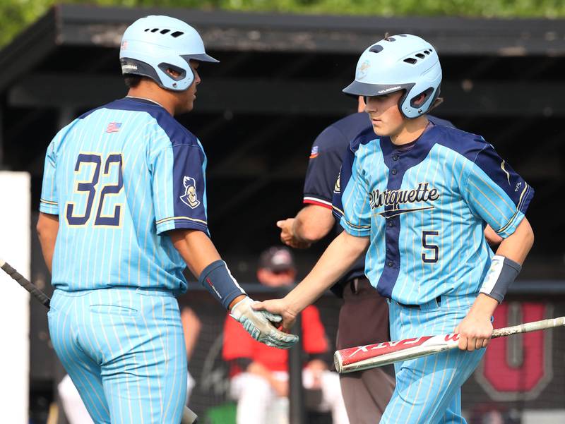 Marquette's Caden Durdan (right) is congratulated after scoring a run by teammate Sam Mitre Monday, June 2, 2025, during their Class 1A supersectional game against Fulton at Northern Illinois University in DeKalb.