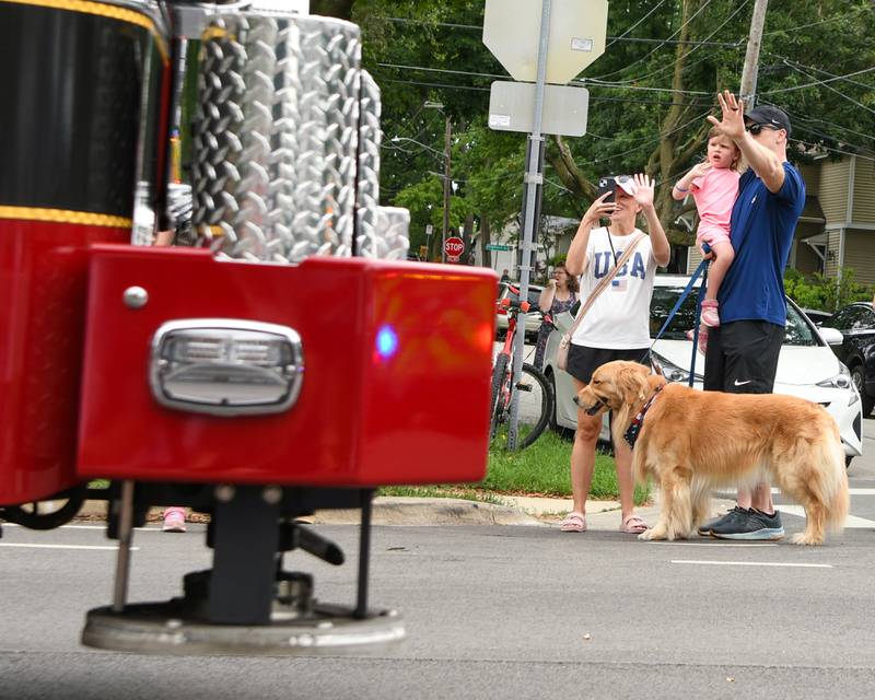 Gina and Dan Blaney along with their daughter Brooke, 3, and their 4 year old golden retriever Mack of Downers Grove, wave as fire trucks pass by during the Independence Day parade on Friday July 4, 2025, held in Downers Grove.