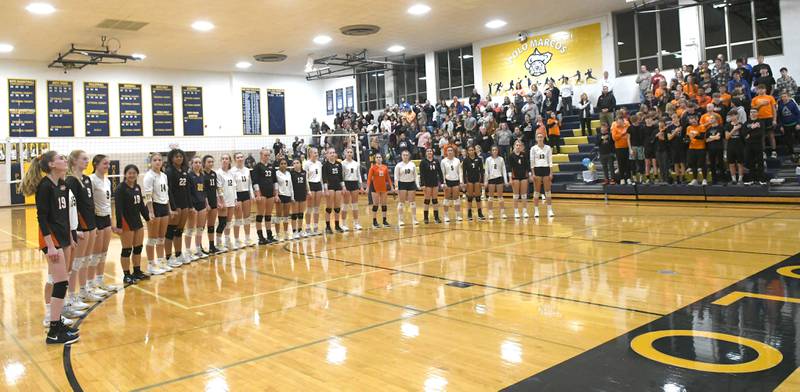 Members of the Polo and Milledgeville volleyball teams hold hands and stand together for the National Anthem prior to the start of their Oct. 13 match in Polo. The Marcos, along with Polo High School staff and students, held a 50/50 raffle, silent auction, and bake sale during the match with with proceeds benefiting two Milledgeville teens who were critically injured during an auto accident on Sunday, Oct. 9. Marcos fans were also asked to wear black and orange, Milledgeville's colors.