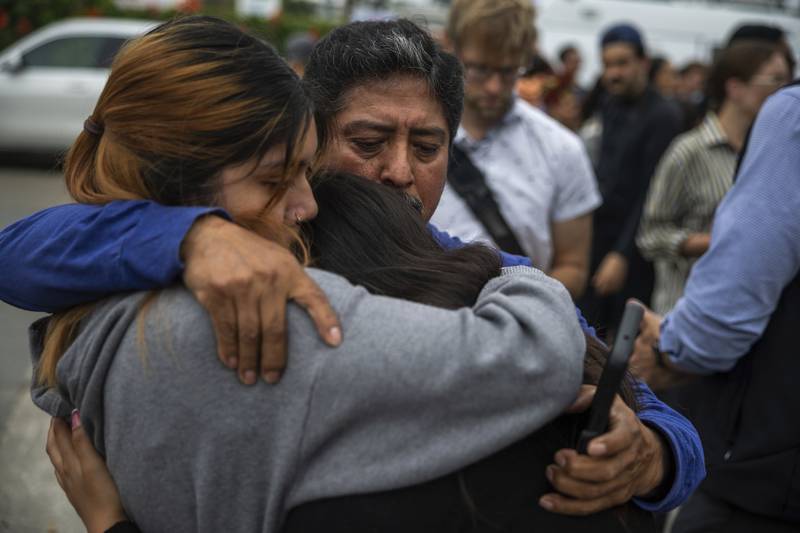 Jaslyn Hernandez, daughter of a car wash worker, embraces her sister Kimberly Hernandez, and their uncle Juan Medina during a press conference with families of detained car wash workers Wednesday, June 11, 2025, in Culver City, Calif. (AP Photo/Ethan Swope)