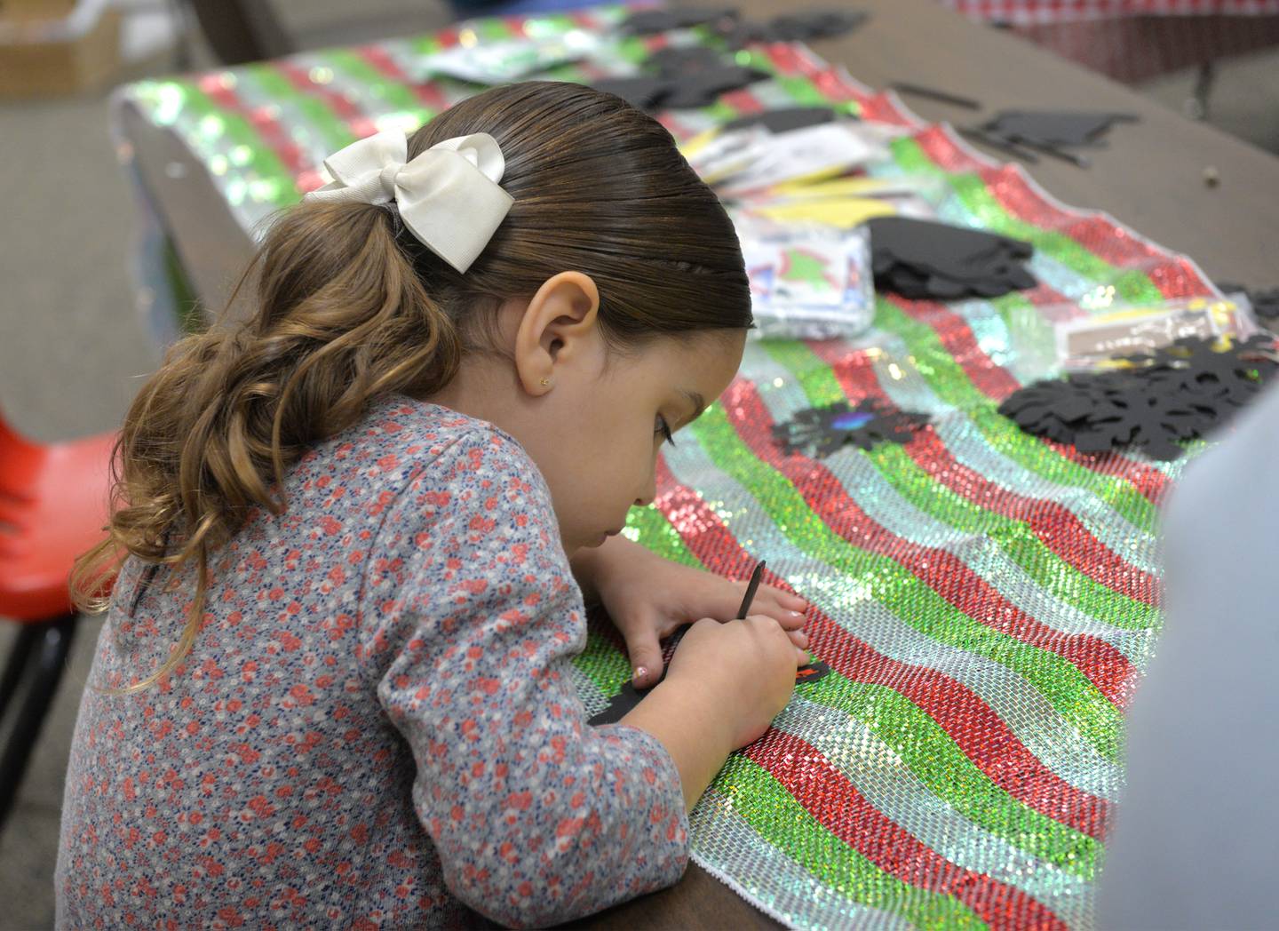 Mia Canfield, 4, of Oregon, works on making an ornament during kids activities at Oregon's Candlelight Walk on Saturday, Nov. 25. 2023. The event included Christmas music, shopping specials, and visits with Santa.
