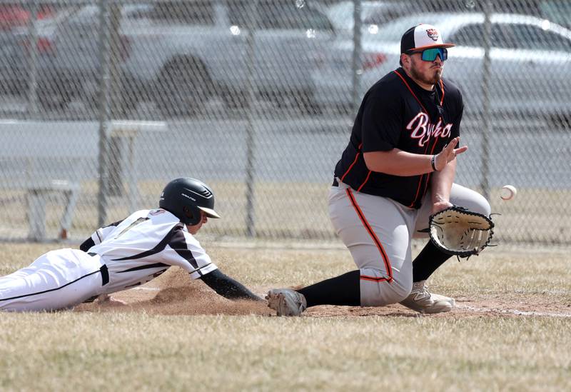 Sycamore's Carter Yoakum slides back safely into first base as Byron’s Nolan Brass takes the throw during their game Wednesday, March 26, 2025, at DeKalb High School. Sycamore’s home field was damaged in last week’s storms so today’s game was played on DeKalb’s field.