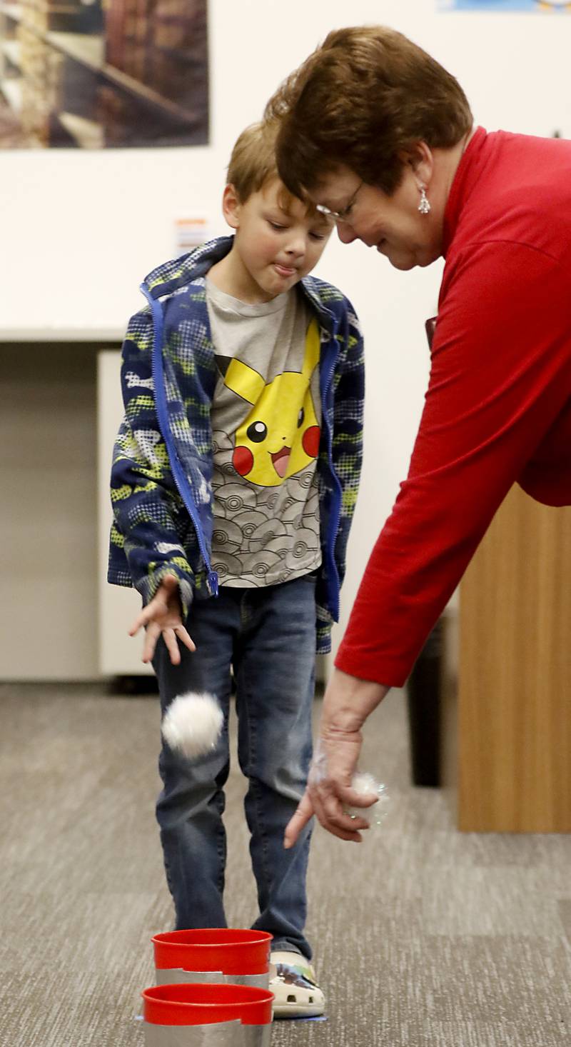 Librarian Denise Wahl points to the bucket the snowball needs to land in as her grandson Henry Watson makes the toss on Friday, Dec. 2, 2022, during the Very Merry Huntley Holiday Open House at the Huntley Area Public Library. The event featured  musical entertainment by Andy Huber, reindeer, Santa, a scavenger hunt, face painting, and a snowball toss.