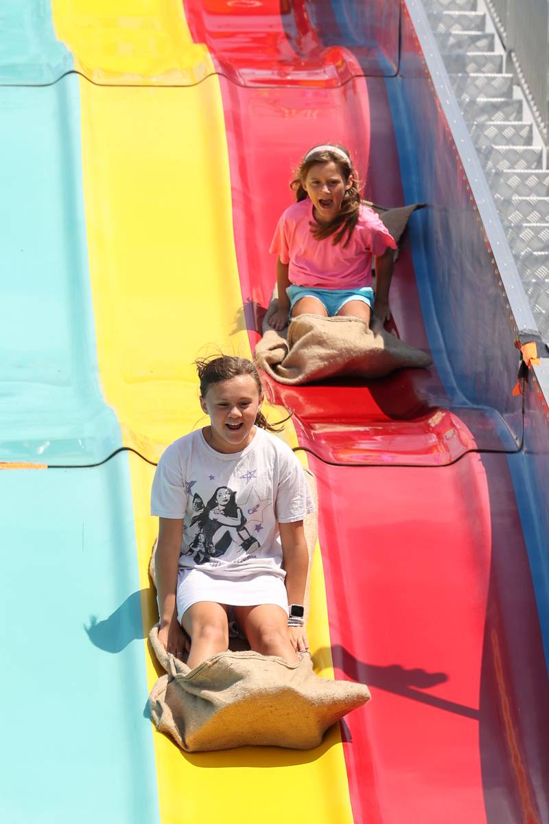 Sisters Vivian Young, 10, left, and Caroline Young, 8, both of Bourbonnais, travel down the Fun Slide at the Kankakee County Fair on Saturday, Aug. 2, 2025.